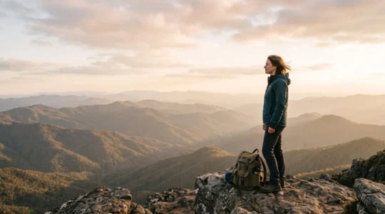 A hiker pausing thoughtfully at a scenic overlook during a well-paced multi-day hiking trip