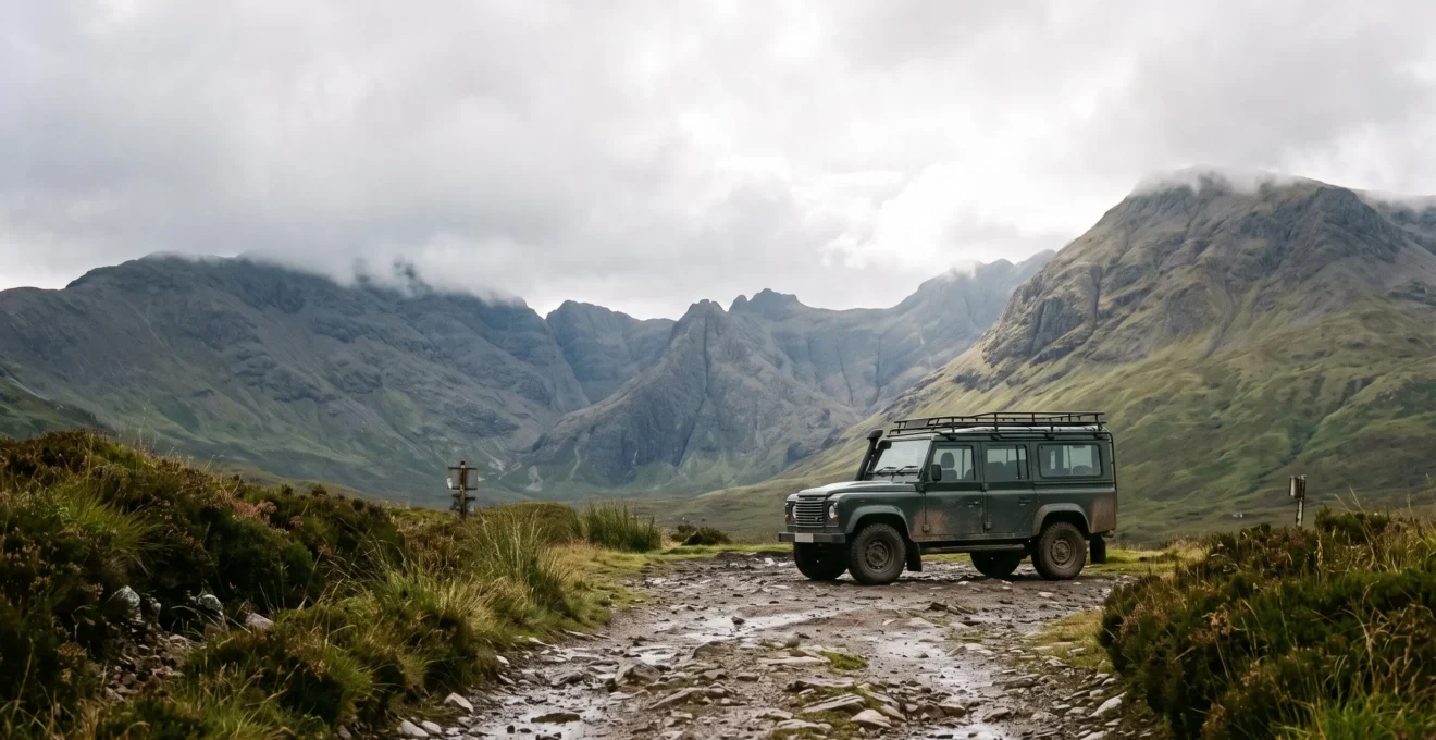 A rugged all-terrain vehicle parked on a rocky, rain-soaked mountain track leading toward misty UK highland peaks